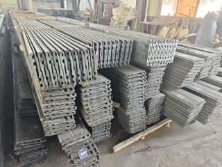 Neatly organized stacks of grey industrial panels with grooved profiles inside a large warehouse.